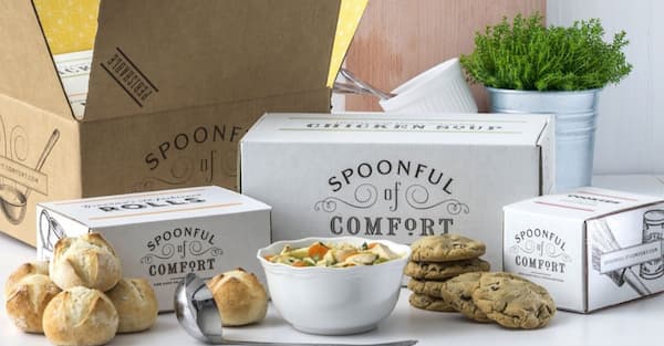 chicken noodle soup, rolls, and cookies in a care package showing the company name Spoonful of Comfort
